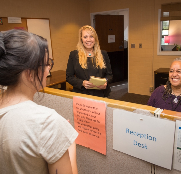 Student with counselors at Counseling Center reception desk
